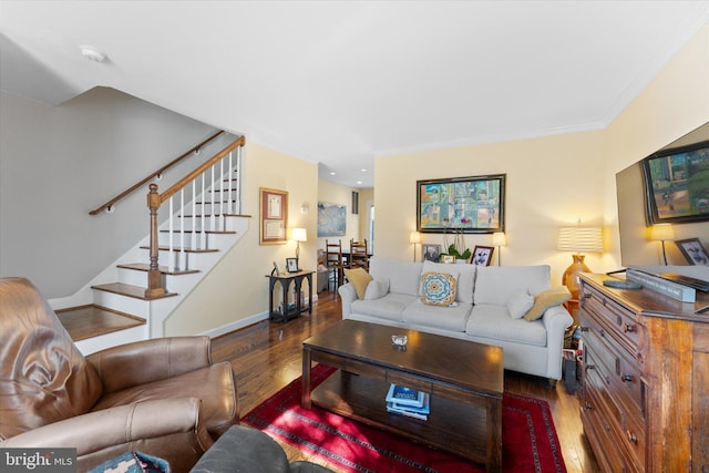 living room featuring baseboards, crown molding, stairway, and wood finished floors