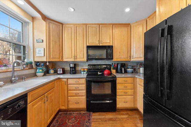 kitchen featuring light brown cabinets, black appliances, a sink, and decorative backsplash