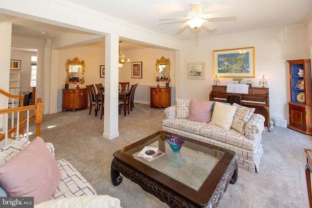 living area with stairs, crown molding, carpet flooring, and ceiling fan with notable chandelier