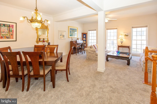 dining area with decorative columns, light carpet, crown molding, and ceiling fan with notable chandelier