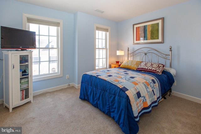 carpeted bedroom with visible vents, multiple windows, and baseboards