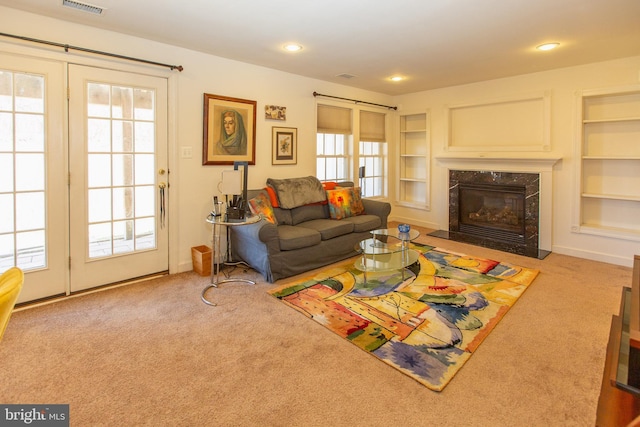 living room with a high end fireplace, visible vents, built in shelves, carpet, and recessed lighting