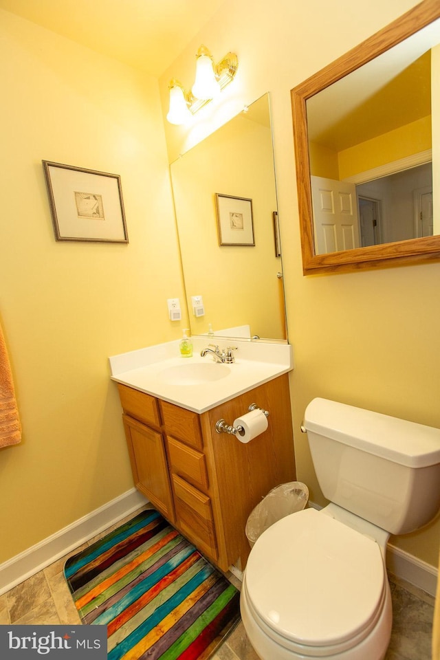 bathroom featuring baseboards, toilet, and vanity