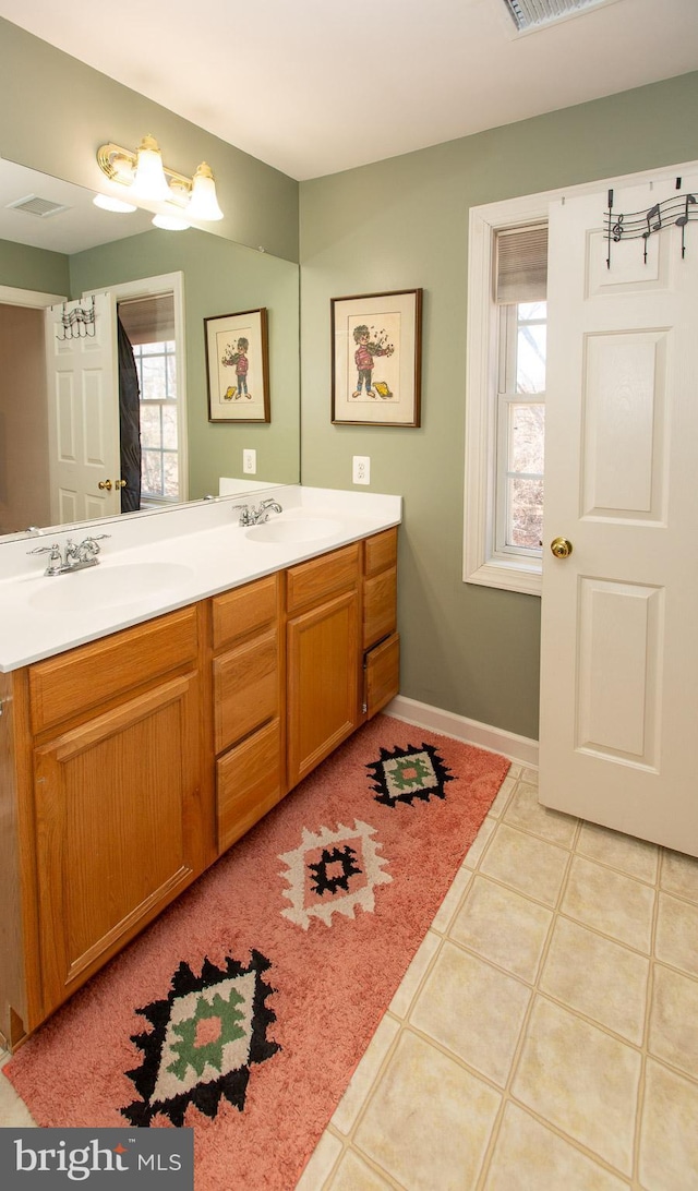 bathroom featuring double vanity, visible vents, baseboards, and a sink