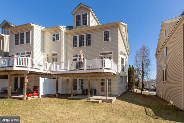 back of house with a wooden deck, a patio, and a lawn