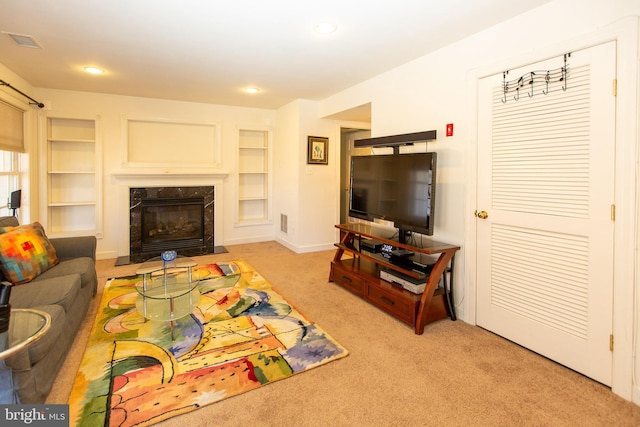 living room with a high end fireplace, visible vents, built in features, light colored carpet, and recessed lighting