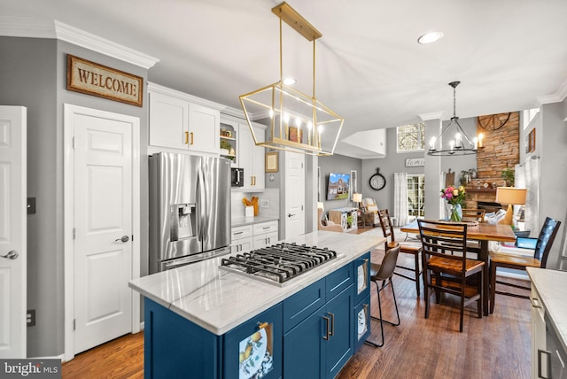 kitchen featuring white cabinets, ornamental molding, appliances with stainless steel finishes, blue cabinets, and a chandelier