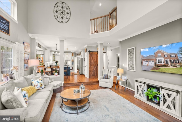 living area featuring a notable chandelier, crown molding, baseboards, and wood finished floors