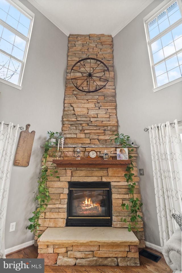 details featuring a stone fireplace, wood finished floors, visible vents, and crown molding