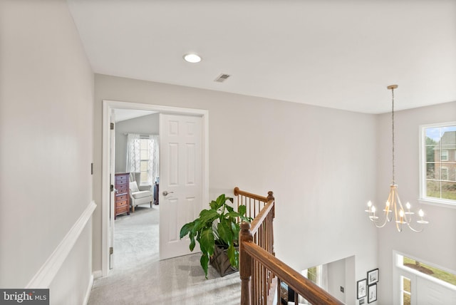 hallway with a notable chandelier, recessed lighting, visible vents, carpet flooring, and an upstairs landing