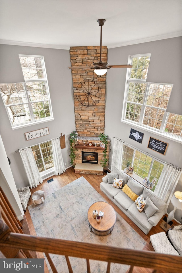 living room with ornamental molding, a fireplace, wood finished floors, and visible vents