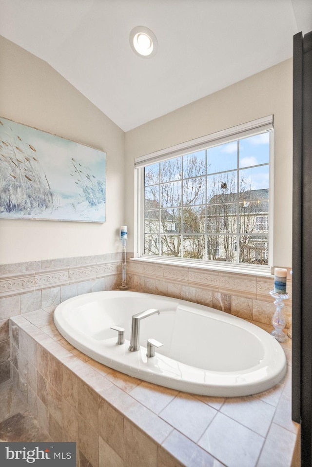 full bath featuring vaulted ceiling and a bath