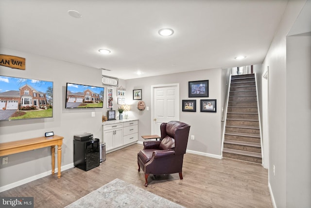 sitting room featuring light wood-type flooring, stairs, baseboards, and recessed lighting