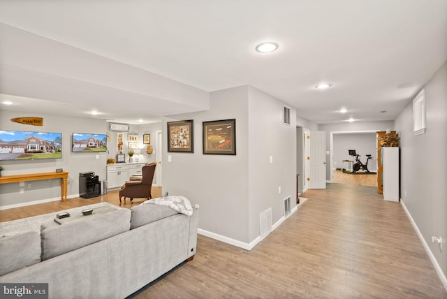 living area featuring light wood-style flooring, visible vents, and baseboards