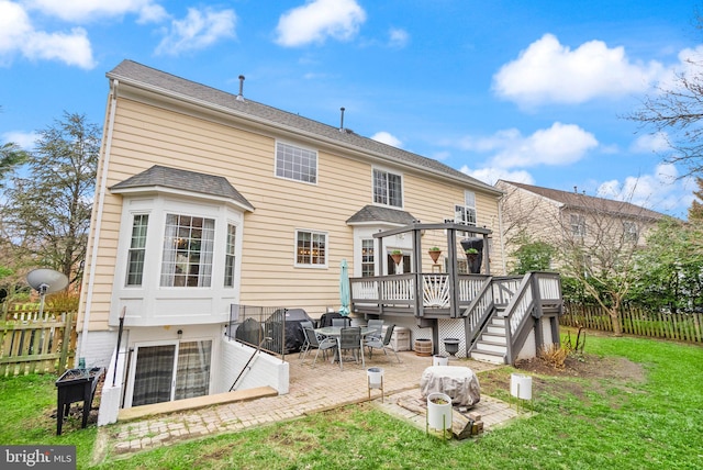 rear view of property with a patio, a lawn, fence, and a wooden deck