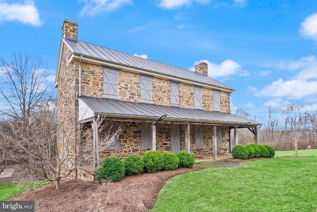 view of front of house with stone siding, a standing seam roof, metal roof, and a chimney