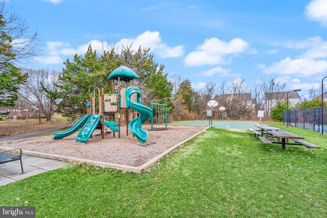 community playground featuring community basketball court, fence, and a lawn