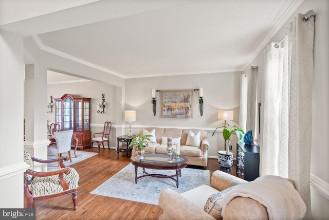 living area featuring ornamental molding, baseboards, and wood finished floors