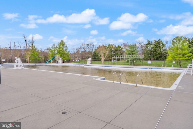 view of property's community with a pool, playground community, and fence