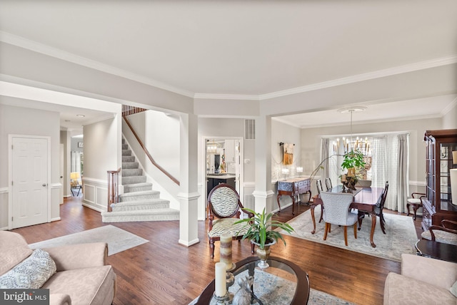 living room with visible vents, an inviting chandelier, ornamental molding, wood finished floors, and stairs