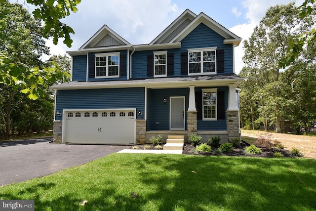 craftsman house featuring a garage, a front yard, stone siding, and driveway