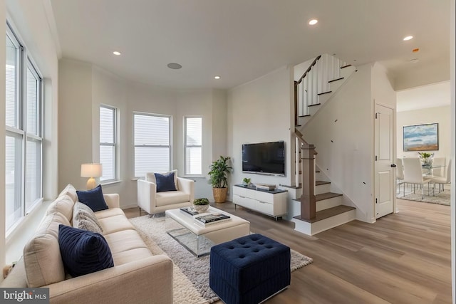 living room featuring a healthy amount of sunlight, light wood finished floors, stairs, and recessed lighting