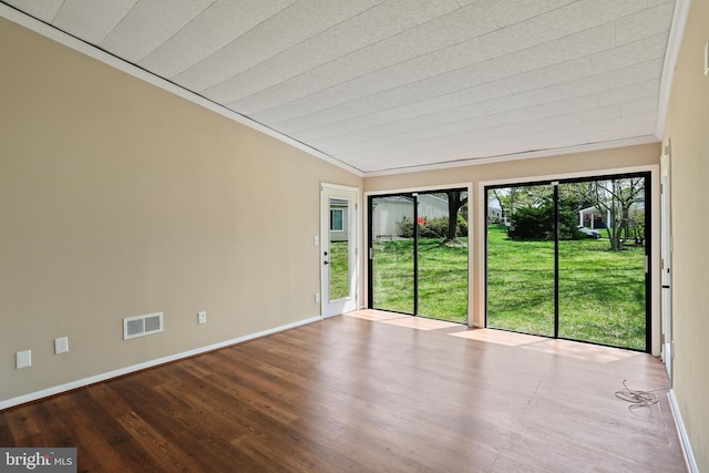 spare room featuring wood finished floors, visible vents, crown molding, and baseboards