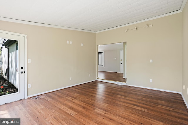 empty room featuring baseboards, ornamental molding, wood finished floors, and visible vents