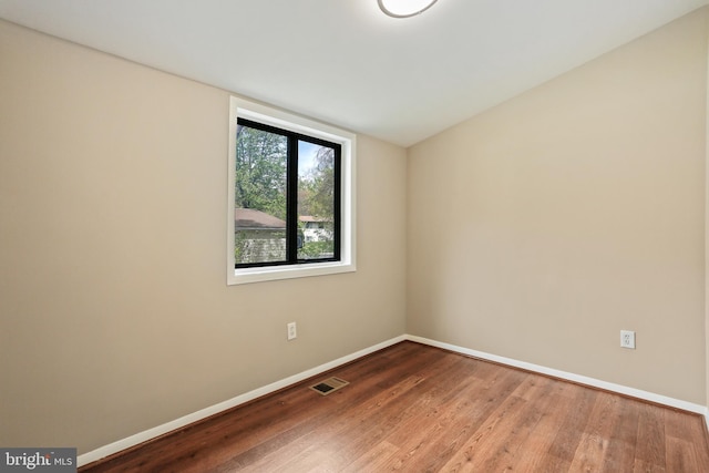 unfurnished room featuring baseboards, wood finished floors, and visible vents