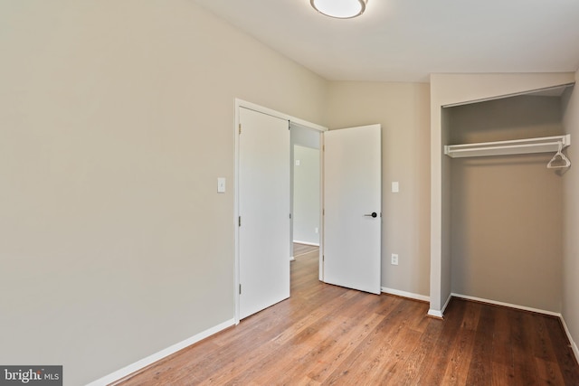 unfurnished bedroom with wood finished floors, a closet, and baseboards