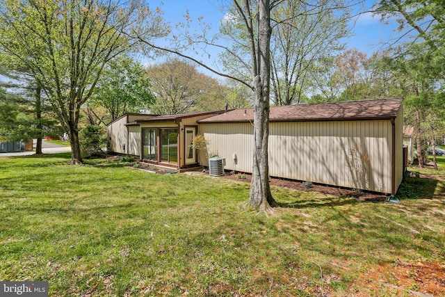 rear view of property featuring a lawn and cooling unit