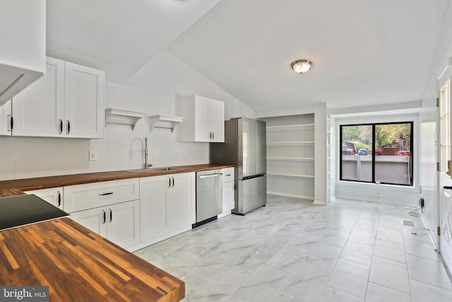 kitchen with stainless steel appliances, a sink, white cabinetry, open shelves, and wood counters