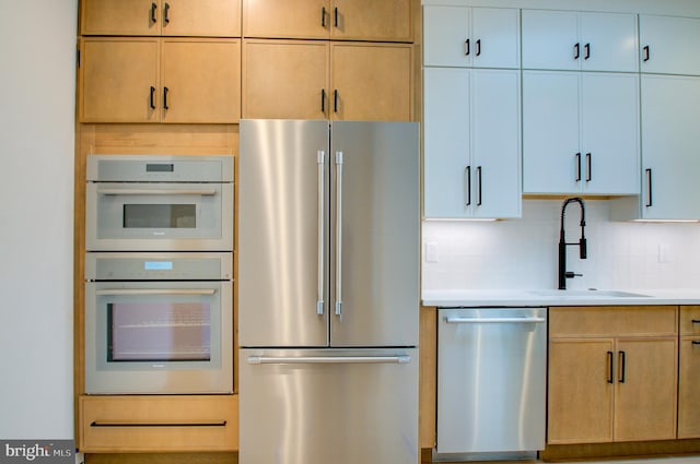 kitchen featuring stainless steel appliances, light countertops, a sink, and backsplash