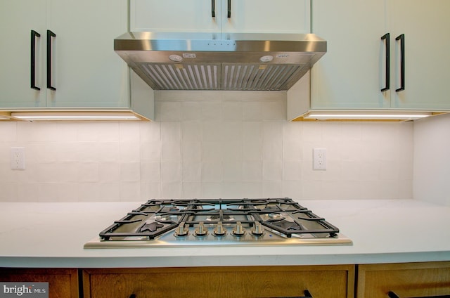 kitchen featuring under cabinet range hood, stainless steel gas stovetop, and backsplash