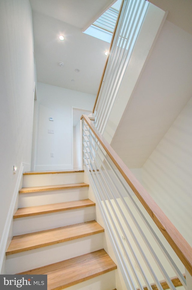 stairs featuring a skylight and recessed lighting