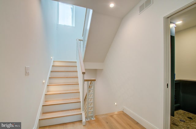 stairway with visible vents, baseboards, and wood finished floors