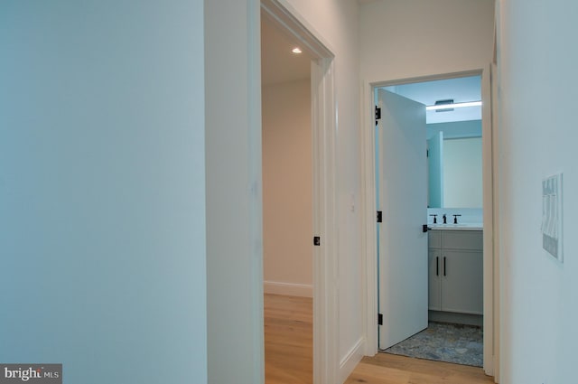 hall with light wood-style floors and a sink