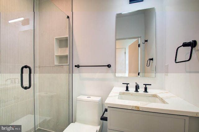 bathroom with toilet, a shower stall, and vanity