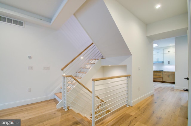 stairs with visible vents, baseboards, and wood finished floors