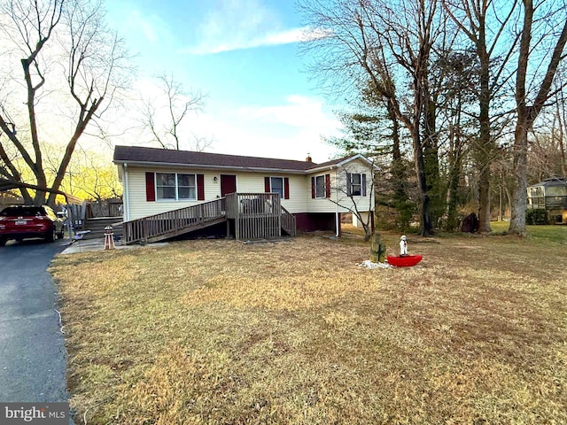 view of front of house with driveway, a front yard, and a wooden deck