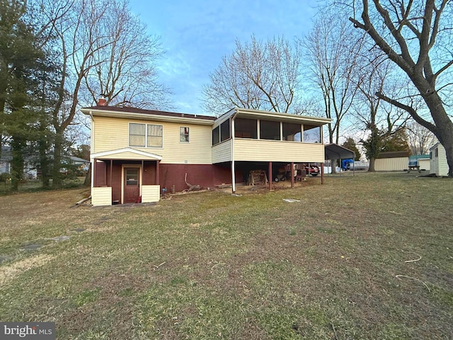 rear view of house with a carport, a sunroom, a lawn, and a chimney