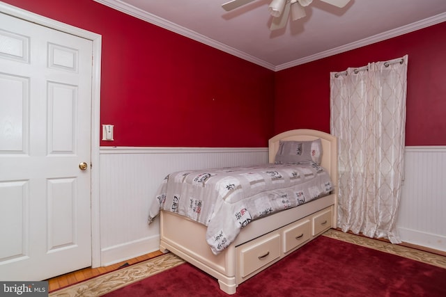 bedroom featuring ceiling fan, ornamental molding, wood finished floors, and wainscoting