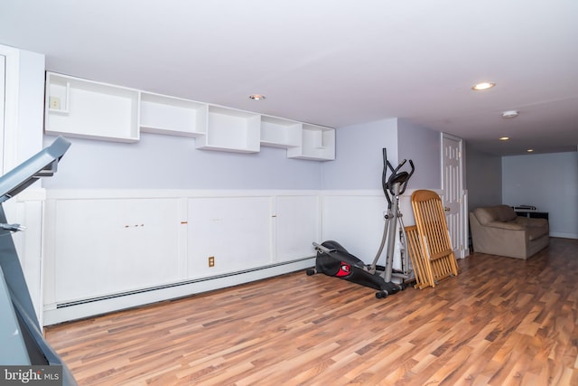 workout room with recessed lighting, baseboard heating, and wood finished floors