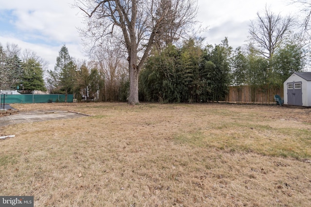 view of yard featuring fence, an outdoor structure, and a shed