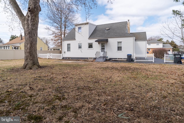 rear view of property with a chimney, fence, a lawn, and roof with shingles