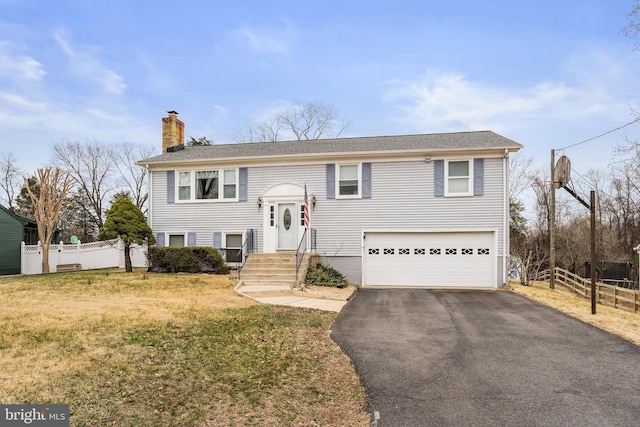 split foyer home with a front lawn, aphalt driveway, fence, an attached garage, and a chimney