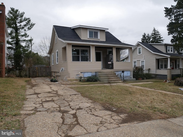 bungalow-style home with a porch, a front lawn, and fence