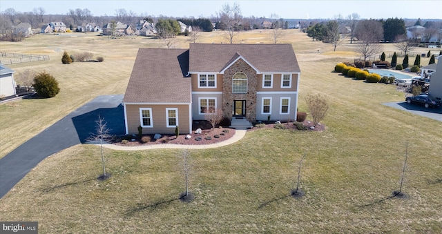 view of front facade with aphalt driveway, a front lawn, and a shingled roof