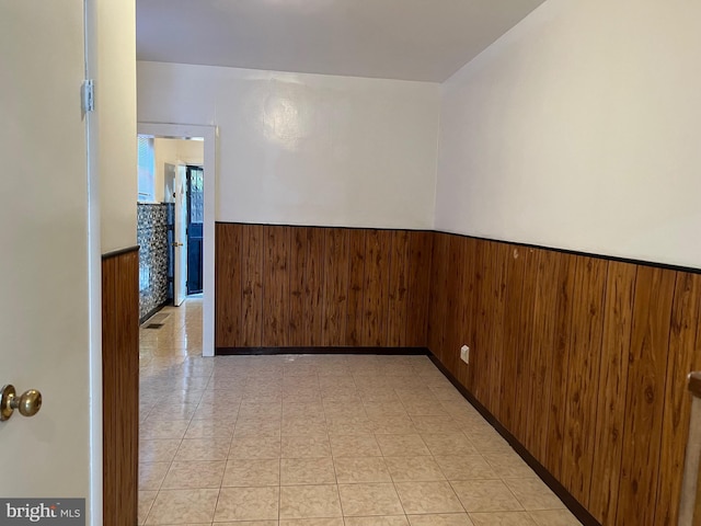 spare room featuring a wainscoted wall and wood walls