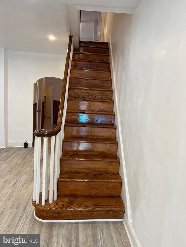 stairway with arched walkways and wood finished floors